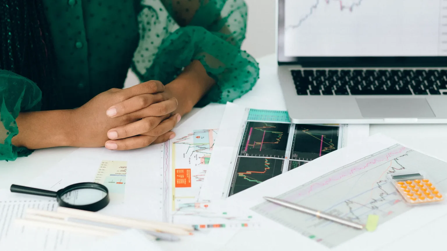 An investor examining printed financial charts and a prospectus with a magnifying glass