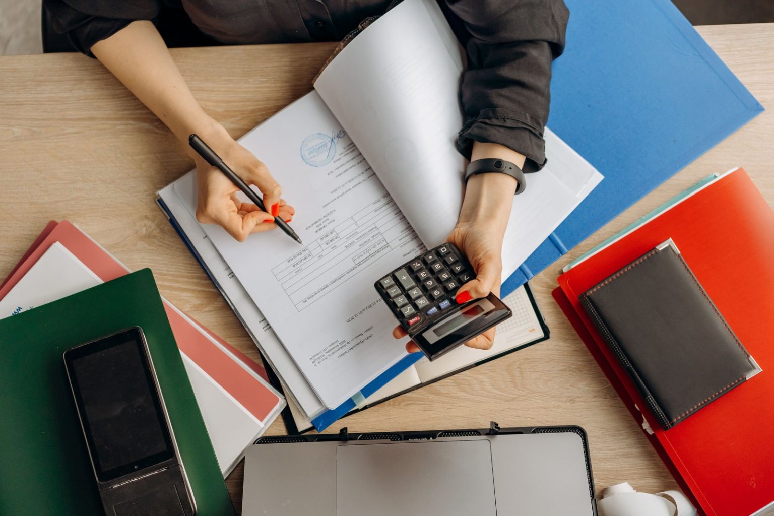 The Financial Habits That Become More Important as a Business Starts to Grow Accountant analyzing financial documents with a calculator on a desk, highlighting business tasks