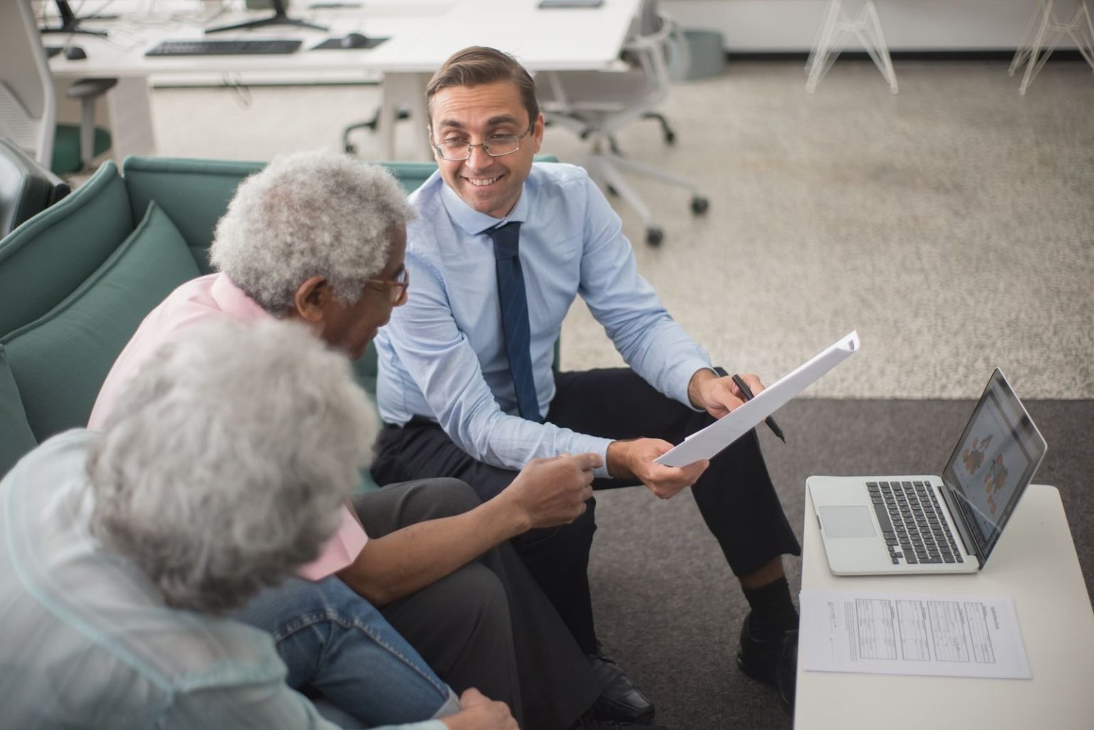 Why Financial Franchises Provide Great Opportunities For Financial Advisers Financial adviser reviewing documents with two senior clients in an office